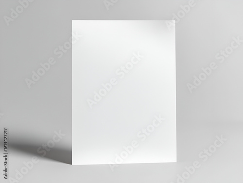Blank white vertical paper or flyer mockup standing on a clean gray surface with a soft shadow.