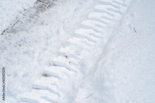 Close-up of tractor tracks on snow-covered cobblestones. Tire tracks on a winter road.