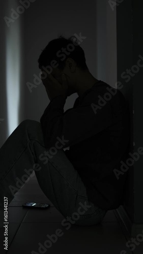 Broken hearted man sitting alone in dark room after breakup. Vertical video