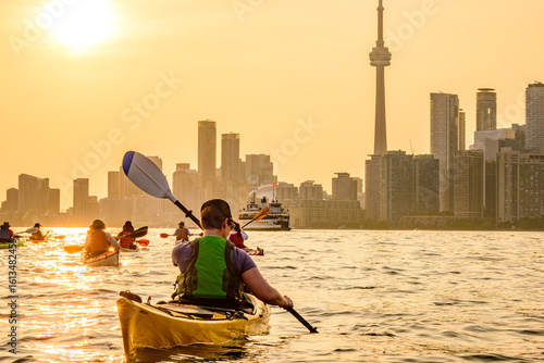 Photography Group of kayakers paddling  into the setting sun and toward the downtown city sk