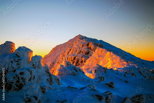 Canvas Print Sunrise colours reflected on snow and the summit of Snowdon mountain, Yr Wyddfa,