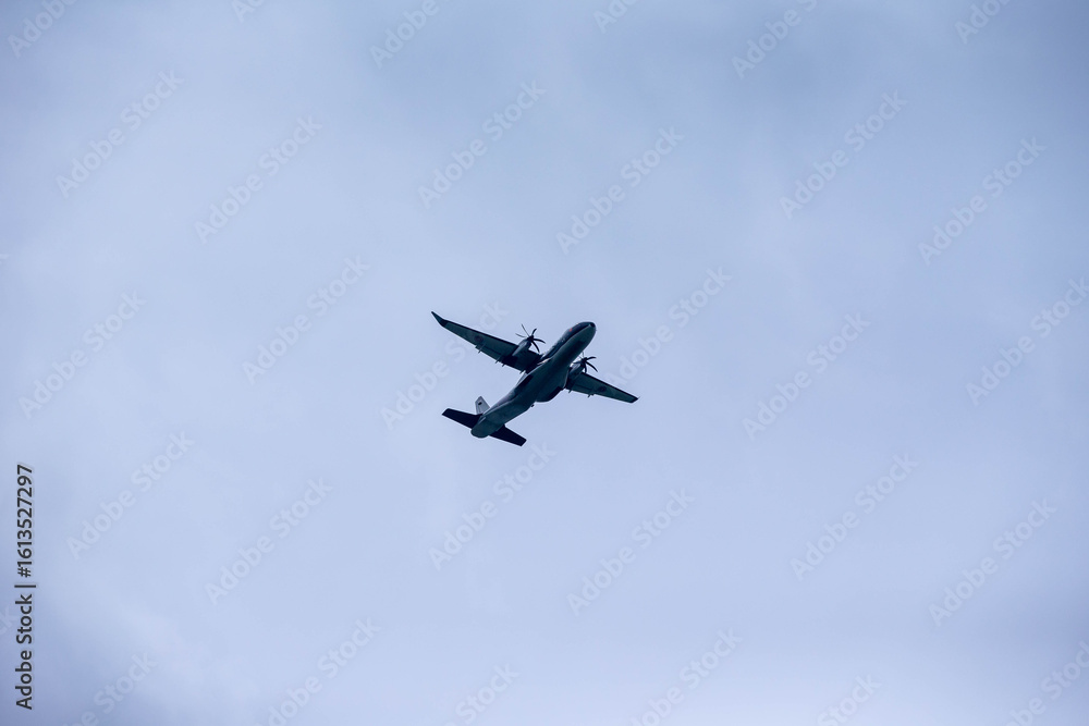 Military Aircraft in Flight, A military transport aircraft flying against a bright blue sky, captured from below during its flight. Military Aircraft in Flight, A military transport aircraft flying against a bright blue sky, captured from below during its flight.