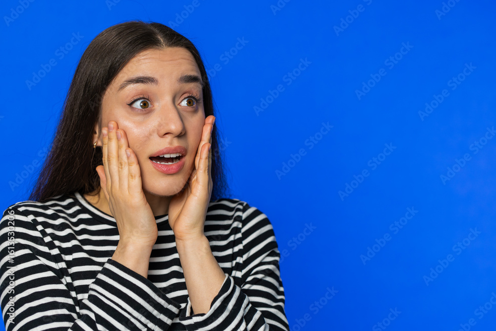 Wow. Excited amazed winner woman raising hands in surprise looking at right with big eyes, shocked by sudden victory celebrating success achievement good news. Girl on blue background. Copy-space Wow. Excited amazed winner woman raising hands in surprise looking at right with big eyes, shocked by sudden victory celebrating success achievement good news. Girl on blue background. Copy-space