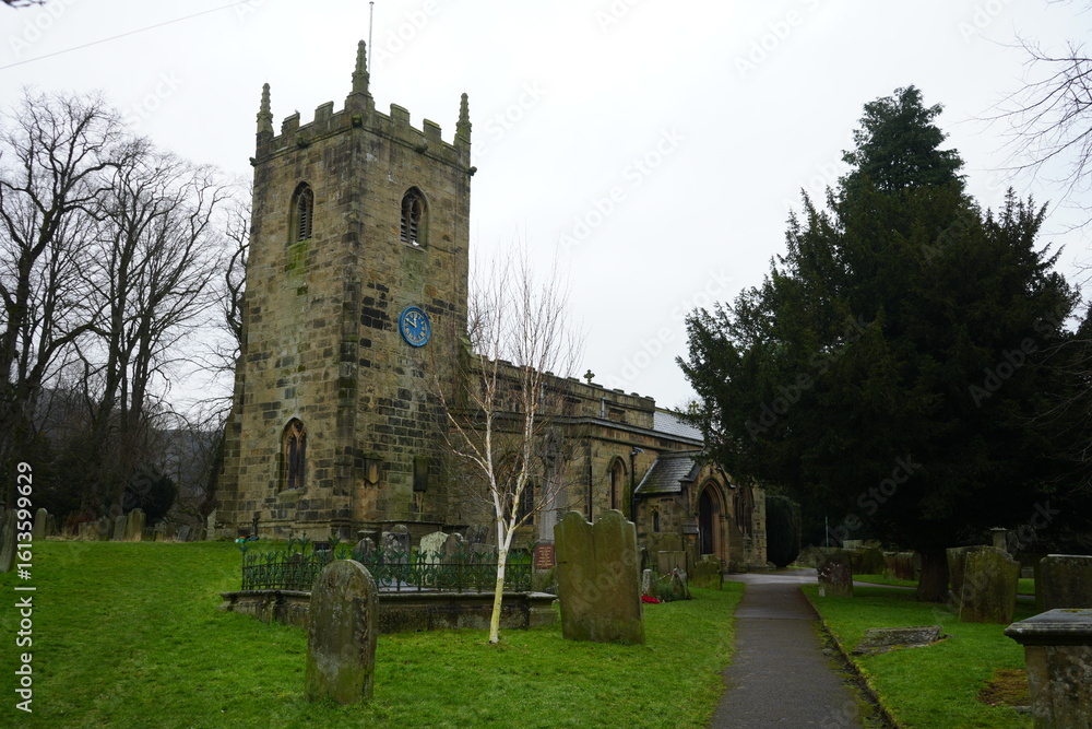 Fototapeta premium Eyam, The Peak District, England – January 21 2025: Stone church and graveyard in the winter light