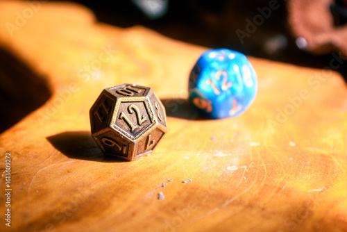 Close-Up Of Metal And Blue D12 Dice On Wood