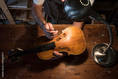 Luthier adjusting the sound post of a violin in his workshop