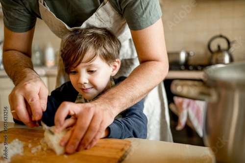 Father teaching son to cut onion in kitchen at home