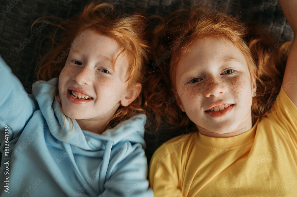 Smiling sisters lying on bed at home Smiling sisters lying on bed at home
