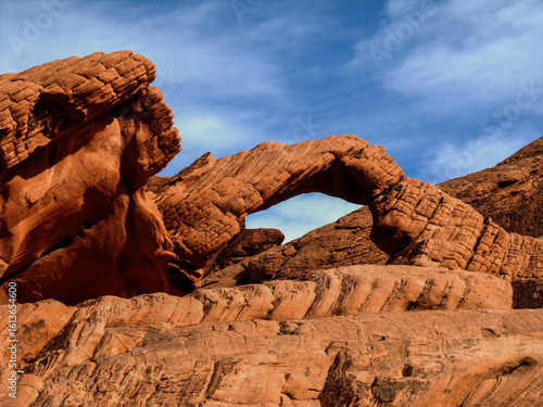 Arch rock, a natural rock arch in the red Aztec Sandstone, in the Valley of Fire State Park in Nevada, USA, against a blue sky.