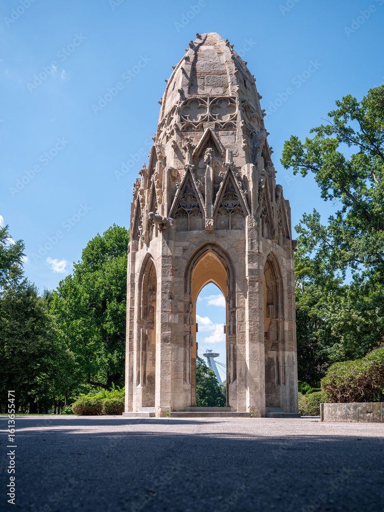 Fototapeta premium Gothic tower in Sad Janka Kráľa park, Bratislava. Originally part of a Franciscan church from the 15th century, now a historic monument surrounded by trees.