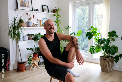 Happy man sitting on stool in living room at home
