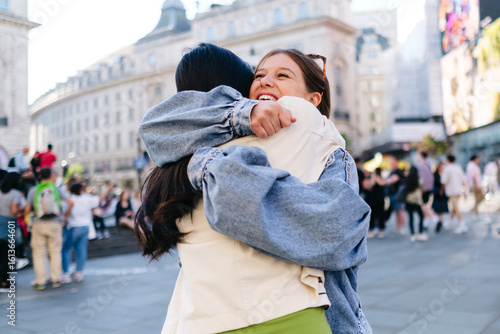 Happy woman embracing lesbian friend in city