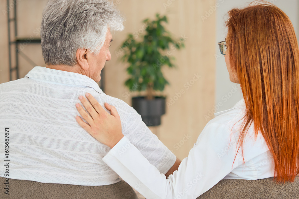 Fototapeta premium Close up of Senior Man with Supportive Medical Professional sitting in a Comfortable Clinic Environment, back view. 