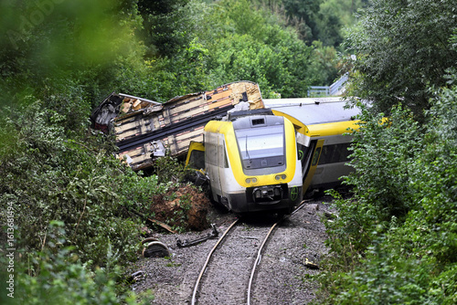 A train accident scene showing derailed and damaged carriages lying motionless.