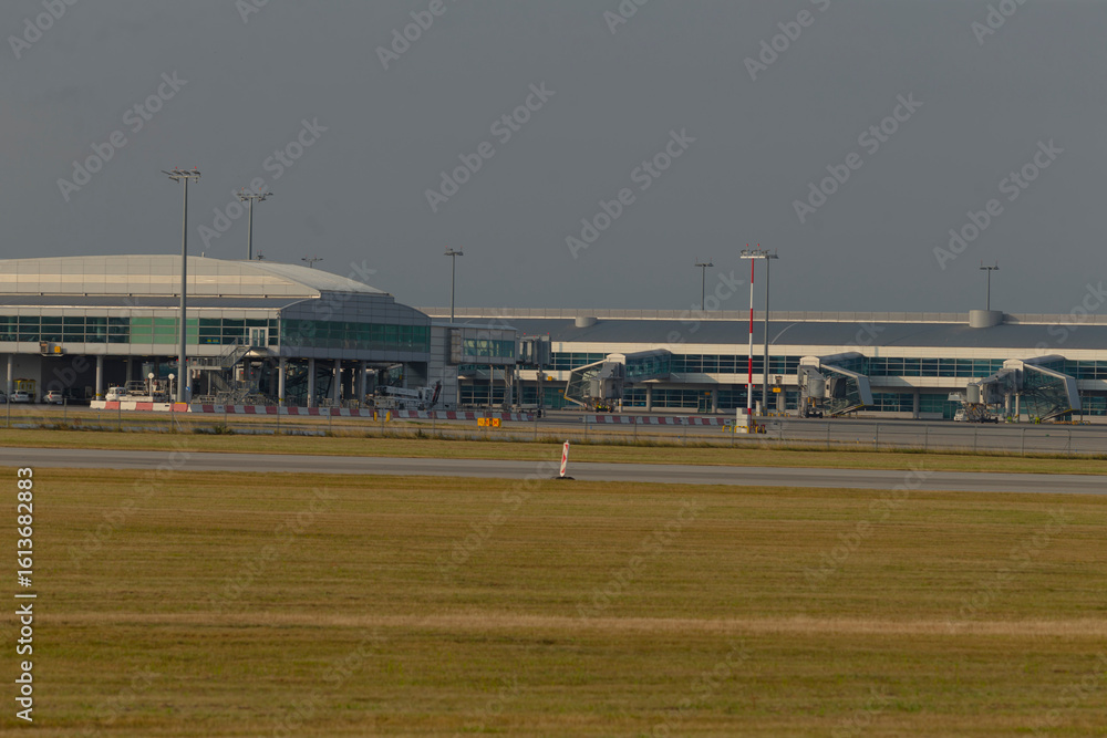 Fototapeta premium A busy airport runway featuring a large building in the background, emphasizing the essential role of aviation in modern transport