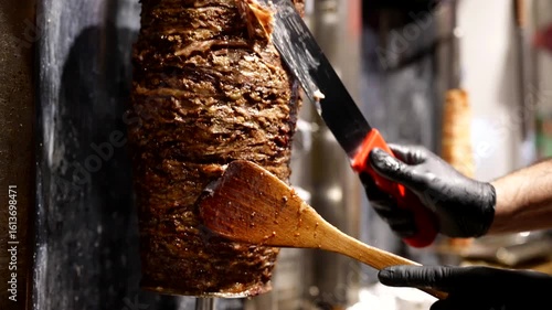 Chef slicing vertical shawarma spit with sharp knife, juicy layers of grilled meat glistening.