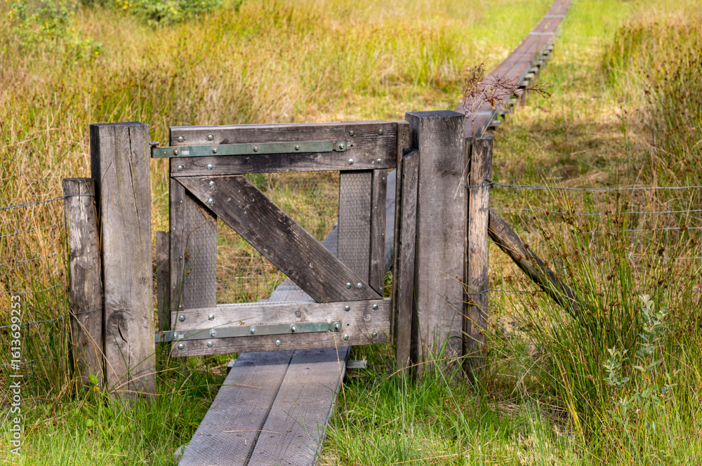 Fototapeta premium Wooden gate protecting a boardwalk through wetlands in woold, netherlands