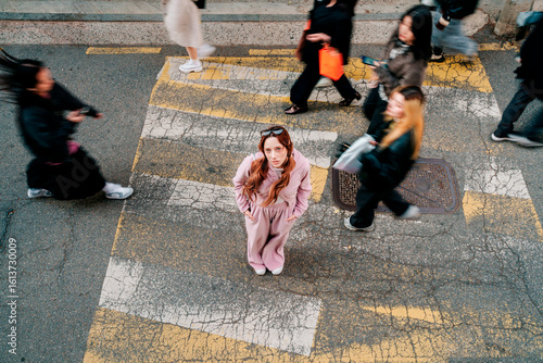 Fashionable person standing on urban crosswalk in Seoul surrounded by people