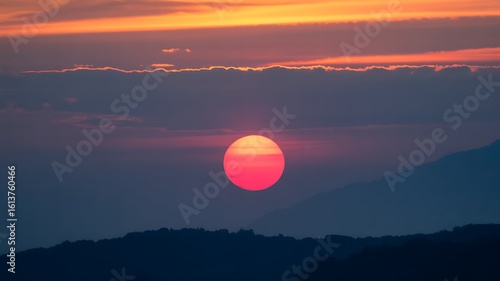 Fiery Sun Setting Behind Silhouetted Mountains sunset