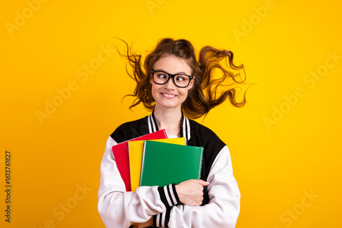 Φωτογραφία Smiling young student holding colorful notebooks in a casual outfit on a bright