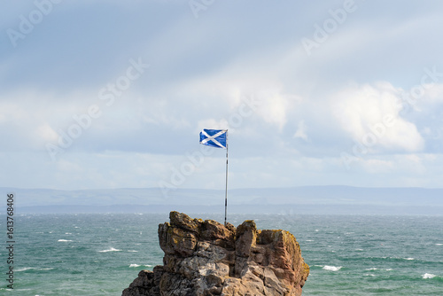 The Scottish flag flying in the wind next to the sea