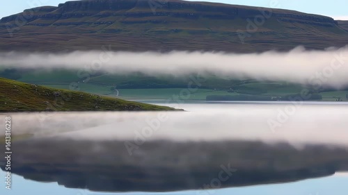 Serene Landscape with Calm Water and Mountainous Horizon Under Soft Morning Light
