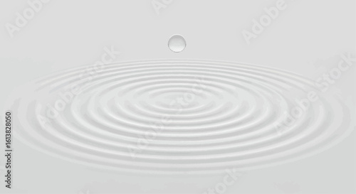 A single droplet suspended above a white surface, creating concentric ripples in the liquid below.