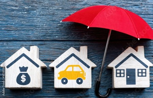 Wooden houses under a red umbrella.  Protection from financial loss