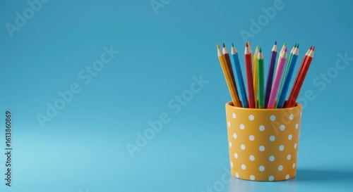 Colorful pencils in a polka-dotted container against a blue background (1)