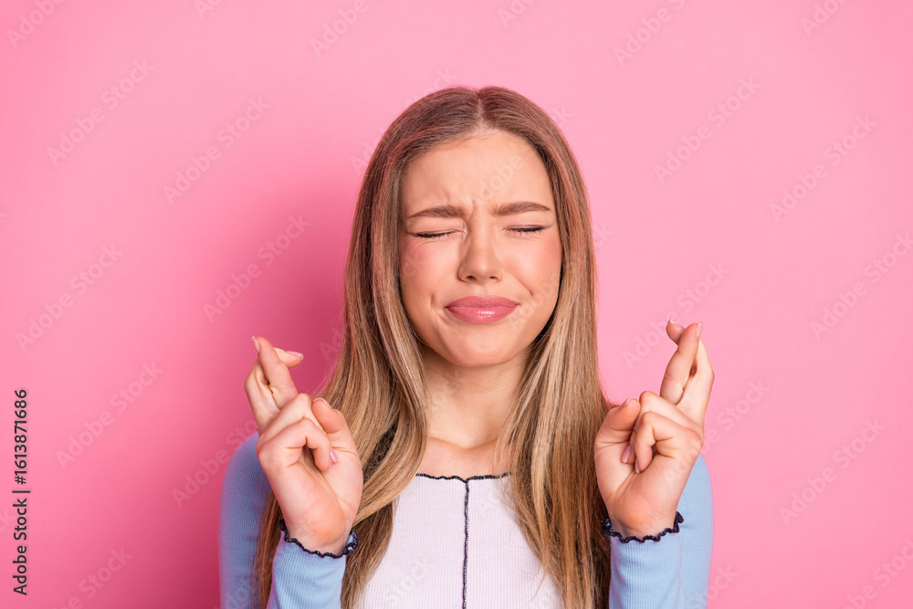 Lovely young woman with a charming smile crossing fingers in hope against a cheerful pink background Lovely young woman with a charming smile crossing fingers in hope against a cheerful pink background