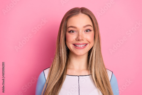 Fotografía Charming young woman smiles confidently with charming braces against a lively pi