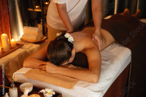 Caucasian woman customer enjoying relaxing anti-stress spa massage and pampering with beauty skin recreation leisure in warm candle lighting ambient salon spa at luxury resort or hotel. Quiescent