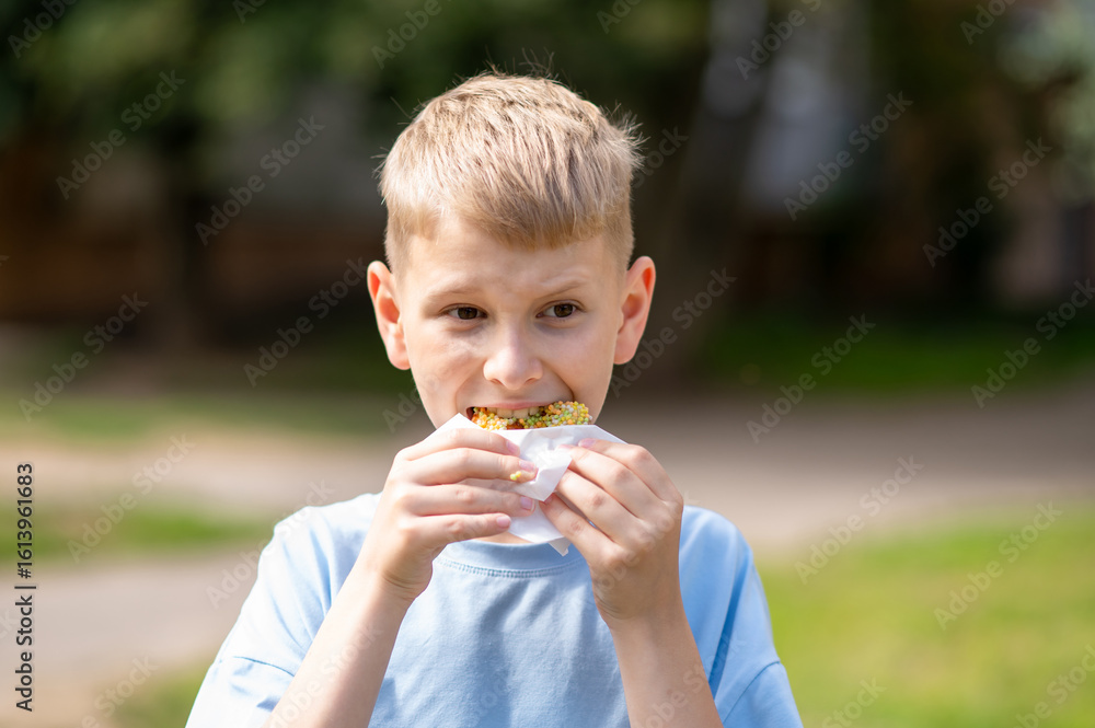 Happy teenage boy eating donut outdoors on a sunny day Happy teenage boy eating donut outdoors on a sunny day