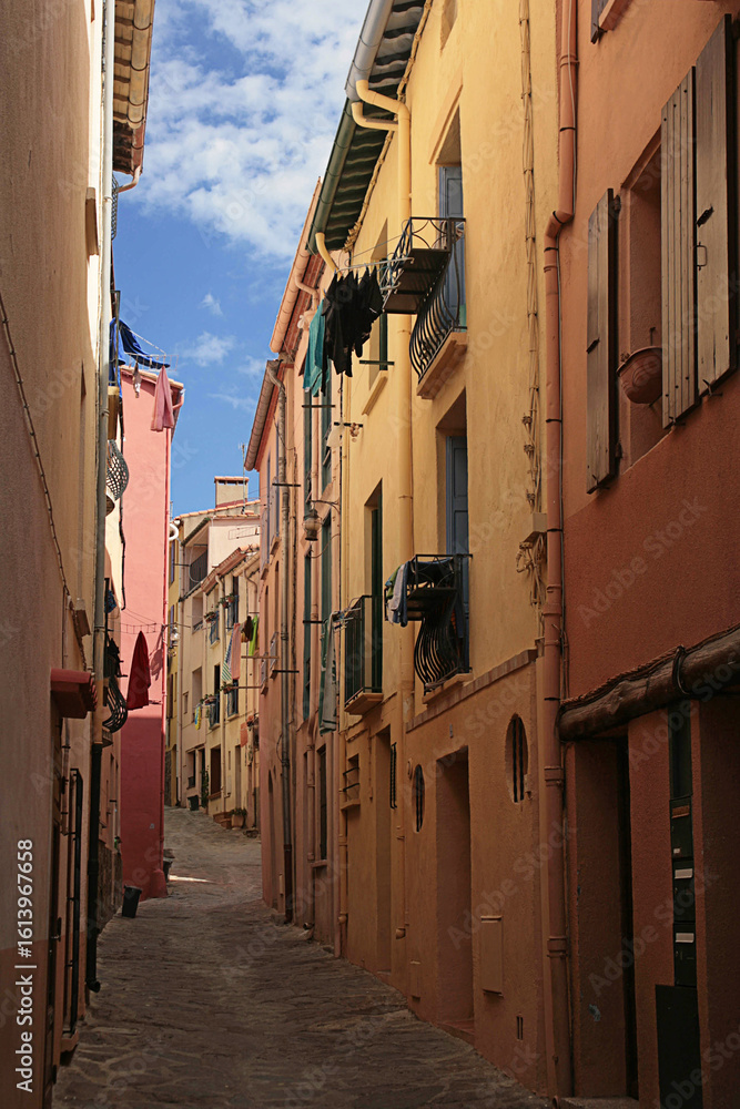 Fototapeta premium Colourful but deserted narrow street (Rue de la Liberté) in Port d’Avall, Collioure, Pyrénées-Orientales, Occitanie, France