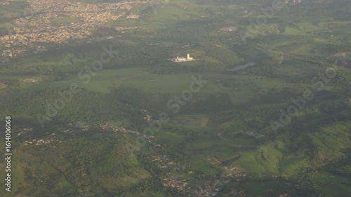 Aerial plane tilt up green landscape to city
