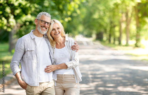 Obraz na płótnie Beautiful mature spouses hugging outdoors while walking in summer park, happy se