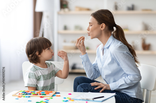 Фотография Young woman speech therapist studying together with small kid, learning practice