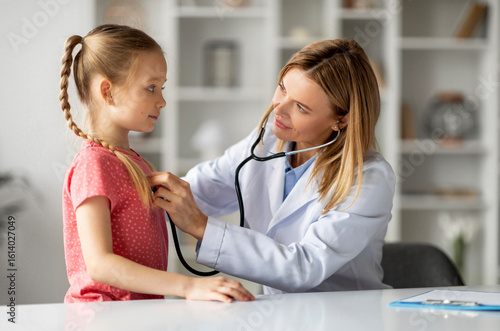 Canvas Print Female doctor checking lungs of little girl during medical checkup in clinic, fr