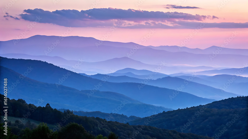 Obraz premium Layers of blue and purple mountains at sunset create a scenic vista