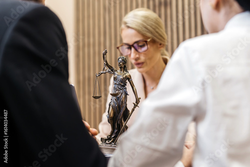Lawyer discussing legal services with clients, showcasing a statue of Lady Justice, symbolizing resolution and fairness in legal disputes and professional guidance