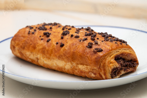 Photography detail view of a chocolate croissant on a white veined marble background