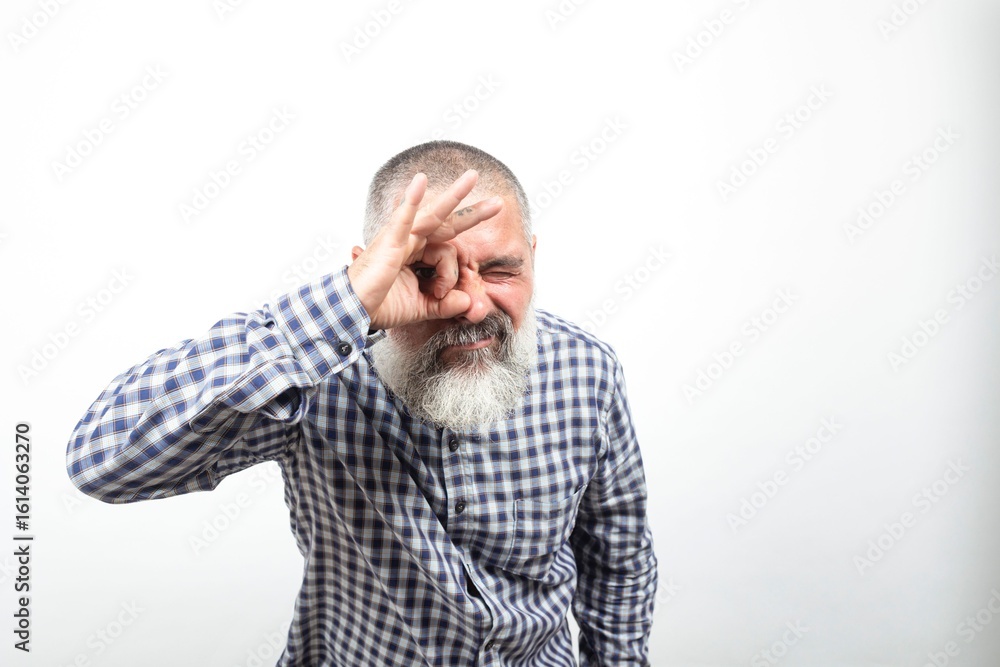 Fototapeta premium Bearded senior man making ok gesture looking through fingers