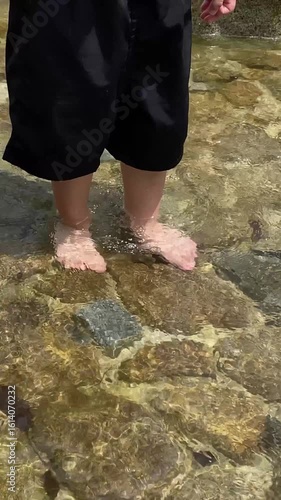 水辺を裸足で歩く子どもの足元（縦動画・手持ち）