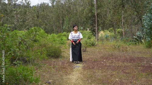 Indigenous woman wearing traditional clothes standing in a forest