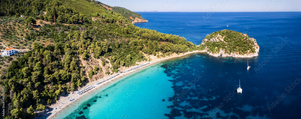 Fototapeta premium Best beaches of Greece. Sporades. Beautiful Skopelos island - Stafilos (Staphylos) with turquoise crystal sea surrounded by green hills. aerial drone panorama