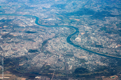Aerial view of Cologne, Germany, with the winding Rhine River, bridges, and city structures on a clear day seen from an airplane