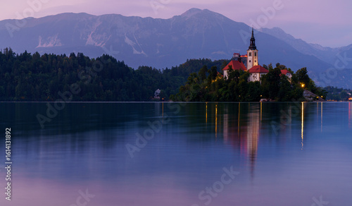 Peaceful twilight over Lake Bled with island church and mountain reflections