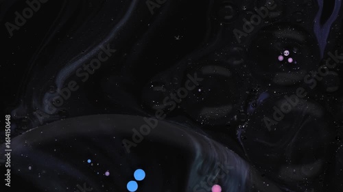 Colorful drops of acrylic paint mix with oil on a dark surface creating fascinating patterns