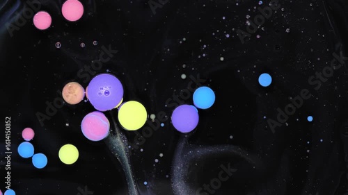 Exploring the mesmerizing interaction of acrylic paint drops in oil on a dark surface