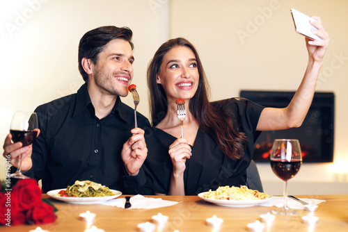 Wallpaper Mural Capturing Moments. Beautiful lovely excited young couple taking selfie while sitting at table and having dinner. Smiling woman and man eating pasta, making photo, having fun at restaurant or at home Torontodigital.ca